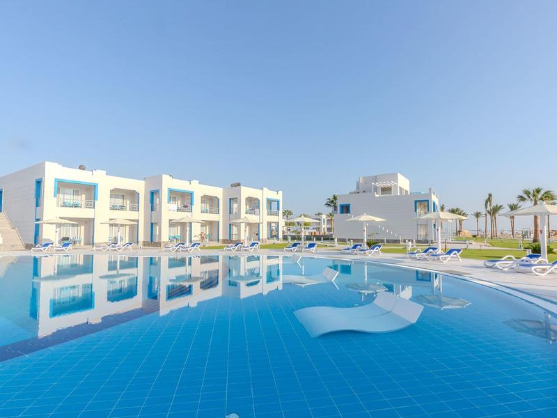 Moderní hotelový bazén s modrými dlaždicemi a lehátky pod jasnou oblohou