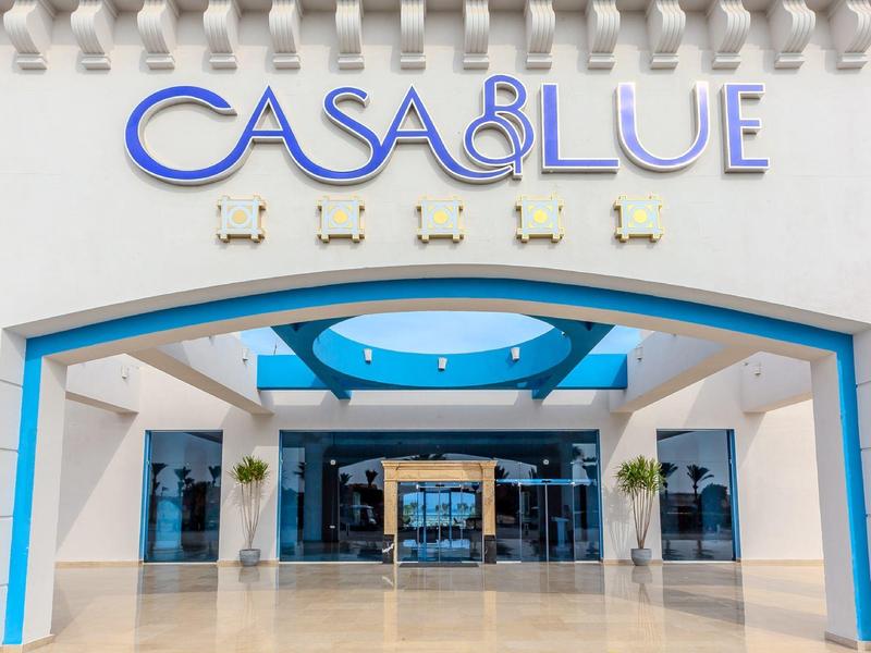 Vstup do hotelu s kulatým modrým stropním oknem a bílo-modrou fasádou