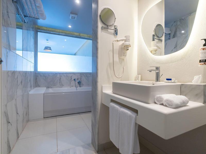 Moderní koupelna s vanou, osvětleným zrcadlem a umyvadlem s ručníky.