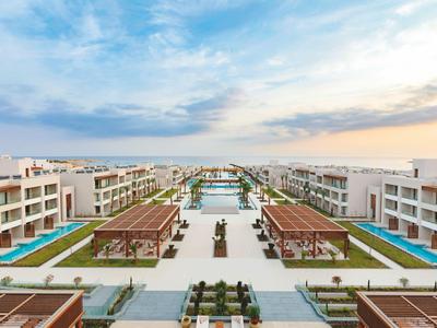 Großes Hotelresort mit Pools und Pavillons unter blauem Himmel bei Sonnenuntergang.