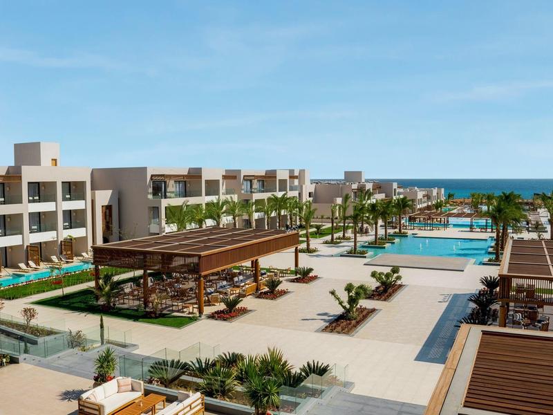 Resort moderno con piscine, gazebo, palme e vista oceano sotto un cielo sereno