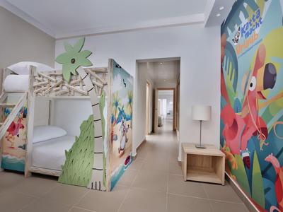 Kinderzimmer mit Etagenbett, bunten Tiermotiven an Wand und Bett, hellem Holz und kleinem Nachttisch.