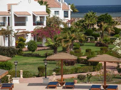 Hotelterras met ligstoelen, parasols en uitzicht op tuin en zee