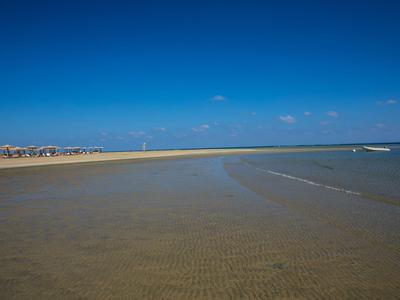 Uitgestrekt strandlandschap met helder water en blauwe lucht bij vakantiebestemming.