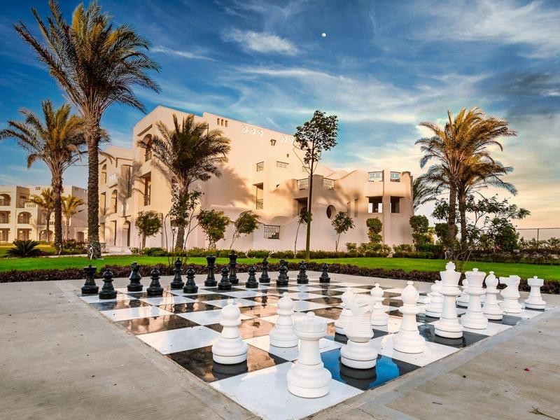 Two people relax in a pool next to a tray of fruit, surrounded by garden and hedges.