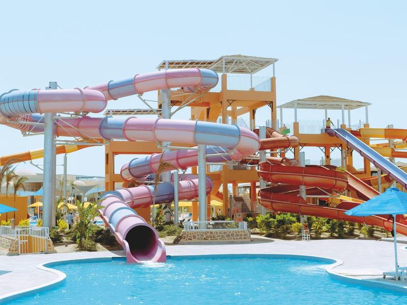 Große Wasserrutschen in verschiedenen Farben und ein klarer Pool unter blauem Himmel.