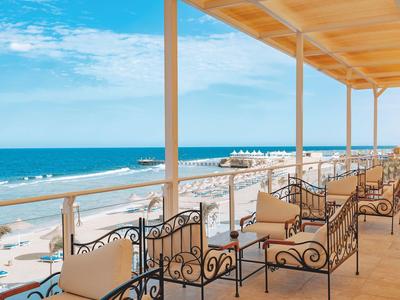 Zadaszony taras z miejscami do siedzenia i widokiem na plażę i morze.