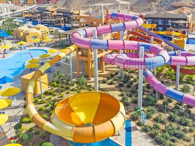 Kolorowy park wodny z dużymi zjeżdżalniami i parasolami w słoneczny dzień.