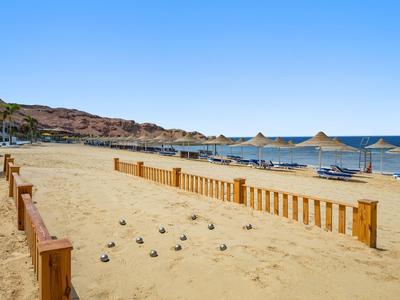 Piaszczysta plaża z parasolami i drewnianym ogrodzeniem pod czystym niebem