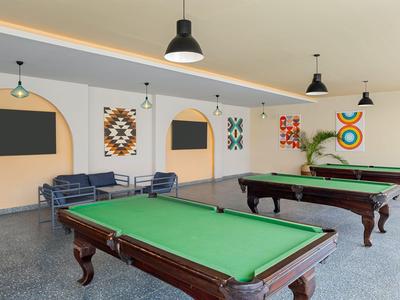 Pokój z stołami do bilarda, sofami i nowoczesnym oświetleniem w centrum rekreacyjnym.