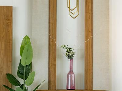 Drewniana dekoracja ścienna z różowym wazonem i zieloną rośliną na podłodze.