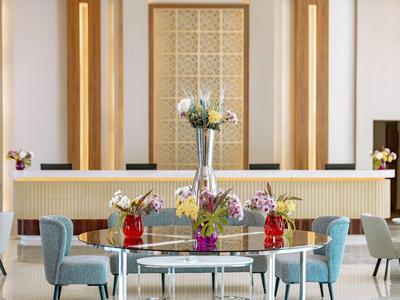 Nowoczesny salon hotelowy z okrągłym stołem i dekoracyjnymi kwiatami na środku.