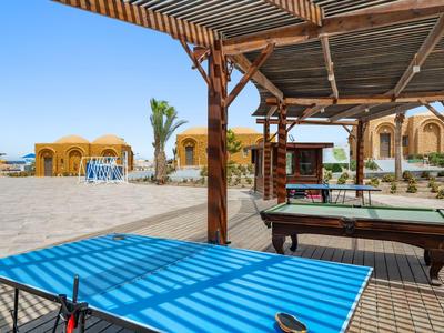 Wiata z bilardem i stołem do ping-ponga obok piaszczystej plaży i parasoli.