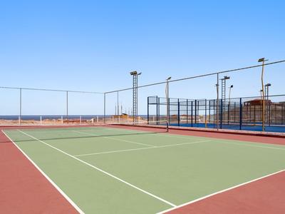 Kort tenisowy na świeżym powietrzu z siatką pod czystym niebieskim niebem