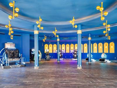 Duże wnętrze z niebieskimi ścianami, żółtymi lampami i drewnianą podłogą w hotelu.