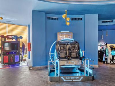 Wnętrze z niebieskimi ścianami i symulatorem jazdy VR na środku.