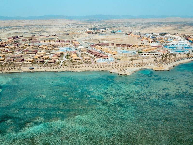 Widok z lotu ptaka na nadmorski kurort z turkusowym morzem i jasną plażą.