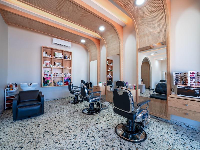 Nowoczesny salon z fotelami fryzjerskimi, półkami z produktami i podłogą terrazzo.