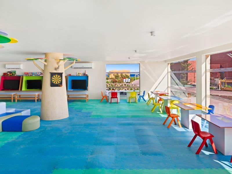 Kolorowy pokój do zabawy z stołami, krzesłami i telewizją w hotelu.