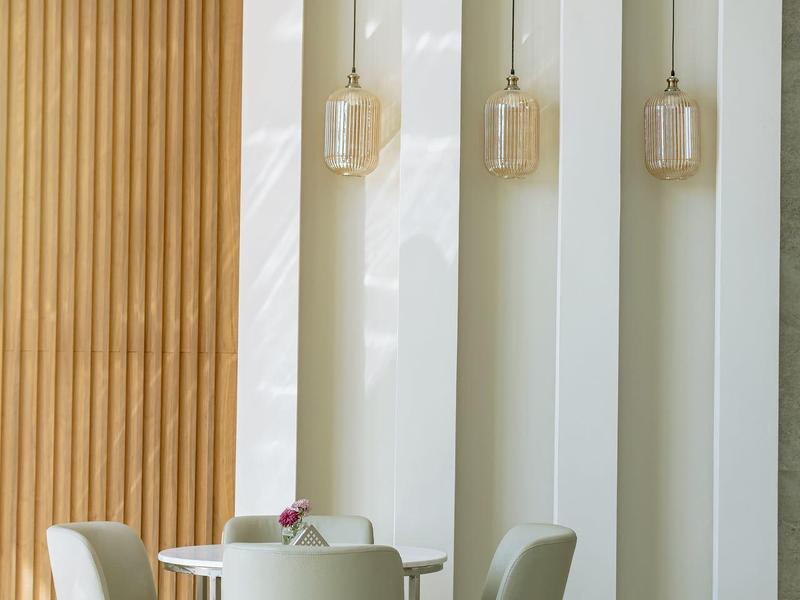 Cztery fotele wokół stołu w jasnym wnętrzu z białymi ścianami i drewnianą ozdobą.