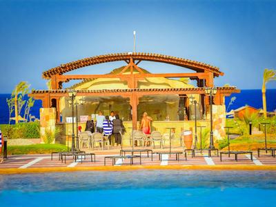 Poolbar mit hellen Holzstrukturen neben einem großen Pool und Blick aufs Meer.