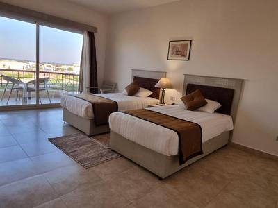 Helles Hotelzimmer mit zwei Einzelbetten, Balkon und Ausblick auf Wasser und Boote.