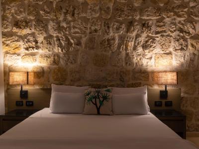 Habitación acogedora con pared de piedra, grandes almohadas y luz cálida.
