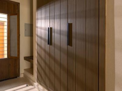 Pasillo estrecho con armario empotrado de madera y luz cálida que proyecta sombras.