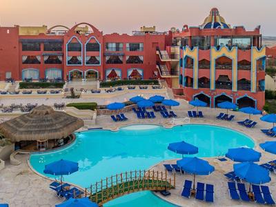 Grande resort con due edifici rossi e una piscina all'aperto con ombrelloni blu e lettini