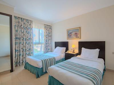 Camera d'hotel con due letti singoli, comodino con lampada e grande specchio.