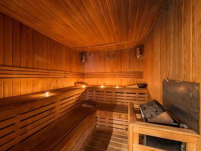 Holzsauna mit Bänken und Saunaofen für entspannende Erholung im Hotelzimmer.