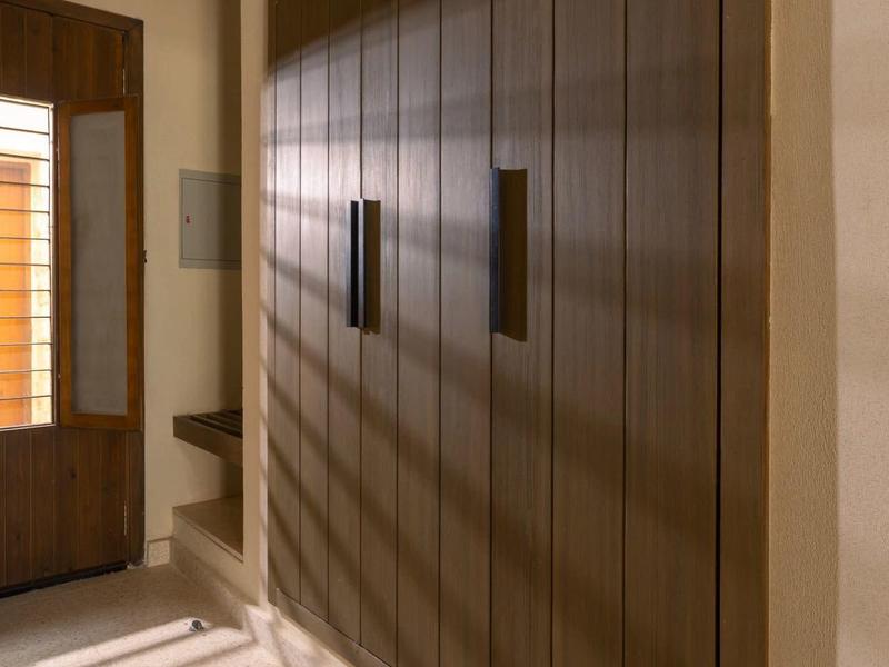 Pasillo estrecho con armario empotrado de madera y luz cálida que proyecta sombras.