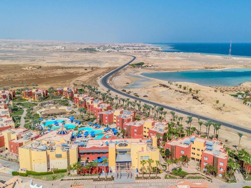 Complejo vacacional con edificios coloridos, piscina y acceso al mar en un paisaje desértico