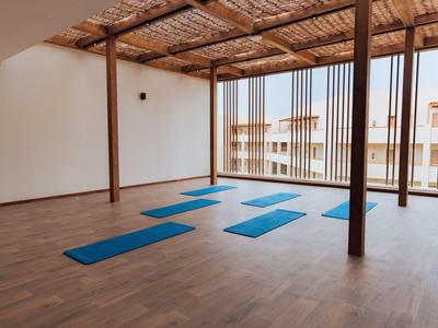 Leerer Raum mit Holzboden, sechs blauen Yogamatten und natürlichem Licht von Gitterfenstern.