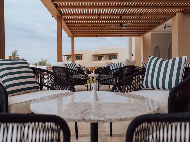 Terrasse confortable avec coussins à motifs et tables en marbre dans un hôtel.