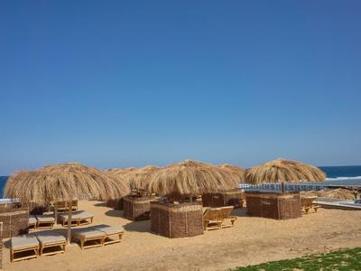 Beach with straw umbrellas and sun loungers under a clear blue sky