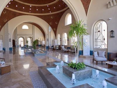 Spacious hotel lobby with high vaulted ceilings, numerous seating areas, and a square water feature.