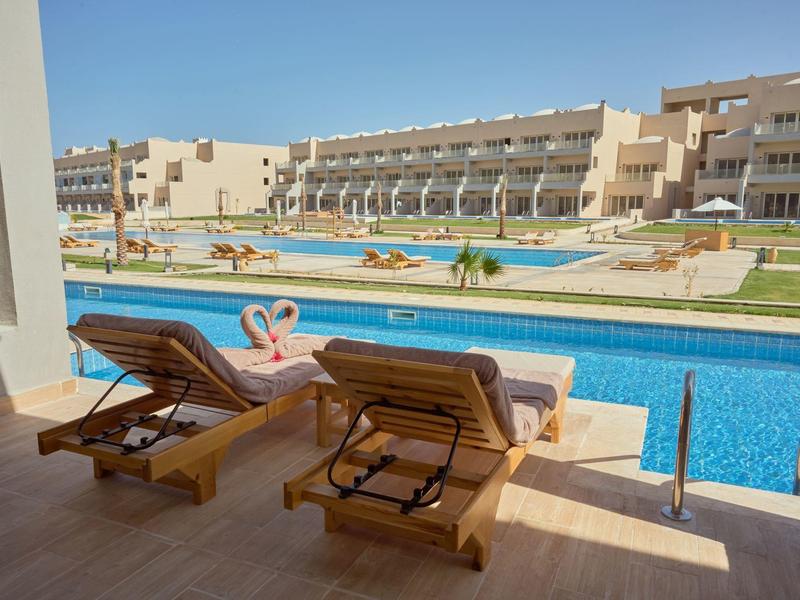 Two lounge chairs by the pool with a view of hotel buildings on a sunny day.