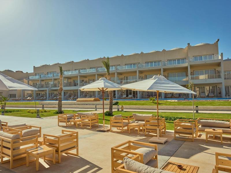 Modern hotel complex with terrace, wooden furniture, and parasols in sunny weather