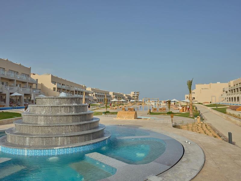 Large fountain in front of modern hotel buildings under clear blue sky.