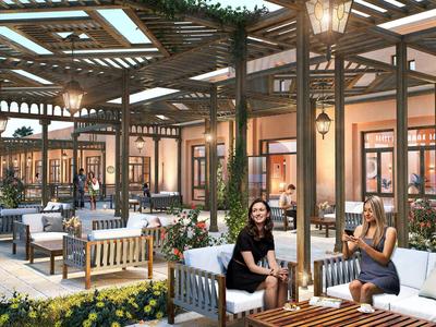 Espace extérieur confortable d'un hôtel avec sièges, plantes et lampes sous un toit en verre.