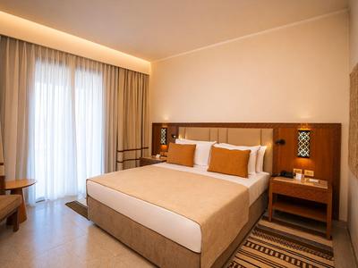 Una camera d'hotel moderna con letto matrimoniale, lampade da comodino e una grande finestra con tende.