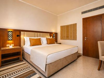 Camera d'hotel moderna con letto grande, comodini e tonalità calde.