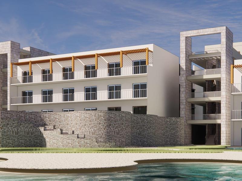 Modern hotel complex with three-story building and pool in the foreground under blue sky.