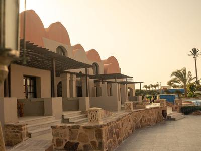 Case a schiera con terrazze e area salotto vicino a piscina e palme al tramonto.