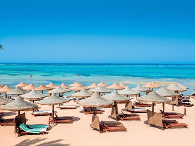 Spiaggia con numerose sdraio e ombrelloni vicino al mare azzurro e limpido.