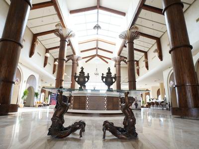 Grande hall d'hôtel avec de grandes colonnes en bois et un comptoir de réception central en arrière-plan