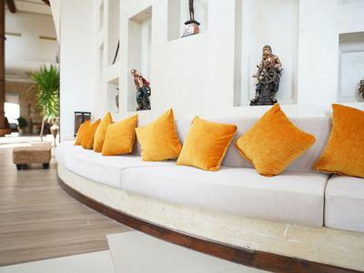 Heller, moderner Lounge-Bereich mit weißem, geschwungenem Sofa und orangenen Kissen.
