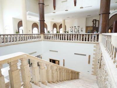 Hall d'hôtel lumineux avec escalier en marbre et rampe décorative, pièce spacieuse avec arches.