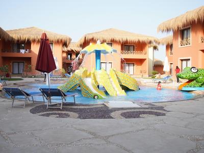 Des enfants jouent dans la piscine avec de grands toboggans et un jouet crocodile dans un hôtel.